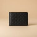 A black leather wallet with an embossed Louis Vuitton monogram pattern, held in a person's hand against a blurred background.