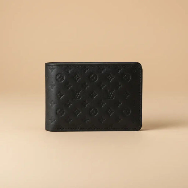 A black leather wallet with an embossed Louis Vuitton monogram pattern, held in a person's hand against a blurred background.