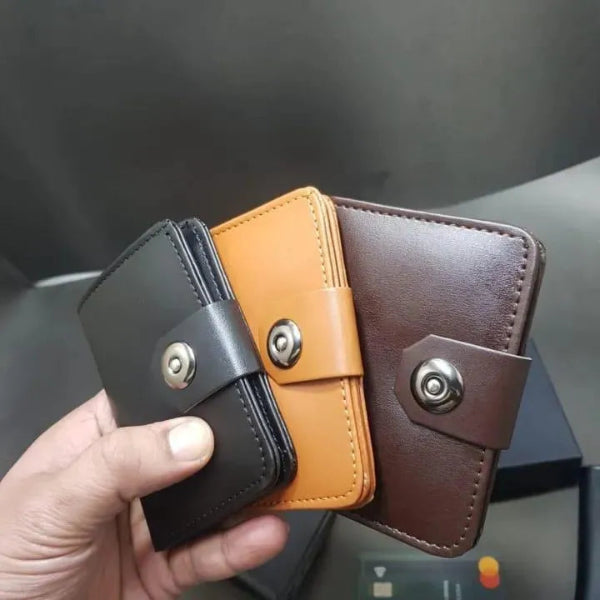 Three leather wallets in black, orange, and brown held by a hand against a dark background.