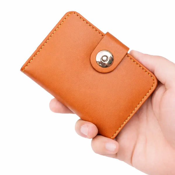 Hand holding a brown leather wallet with a gold button on a white background