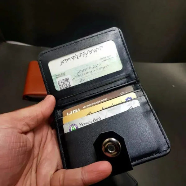 Black wallet with cards held open by a hand against a dark background