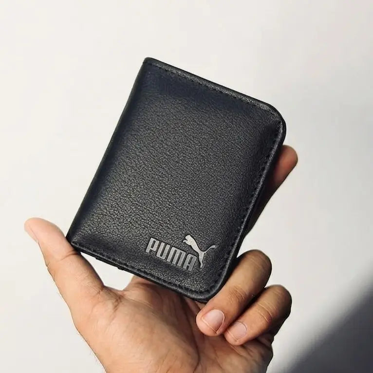 A black textured leather Puma wallet held in a hand against a plain light background.